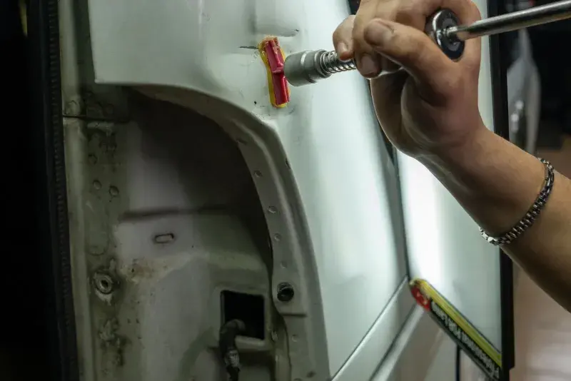 Technician performing paintless dent repair on a car panel at FastLane Mechanics in Mississauga