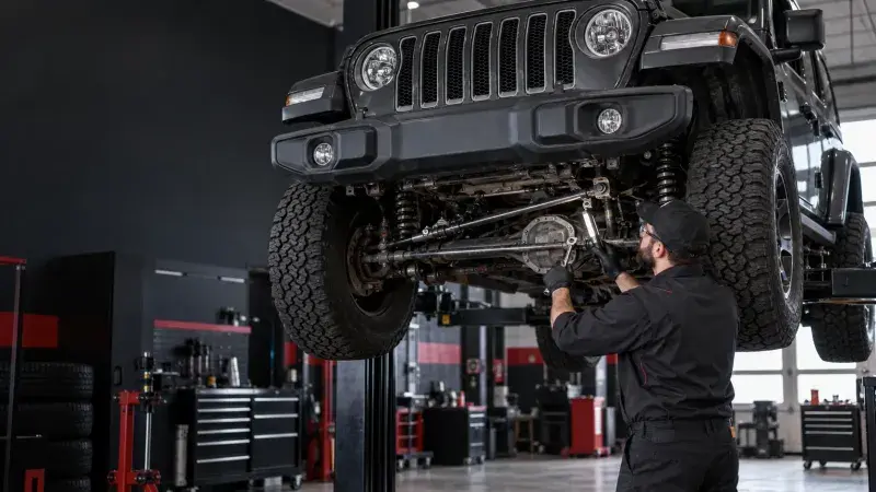 Technician inspecting the front suspension and track bar of a Jeep on a lift at FastLane Mechanics in Mississauga