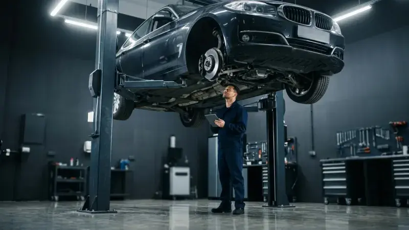 Car raised on a two-post hoist while a technician inspects the underside during a safety certificate inspection at FastLane Mechanics in Mississauga